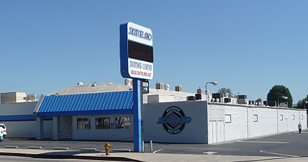 The Skateland building on Parthenia Street, a white building with a blue awning and a tall Skateland sign beside the parking lot